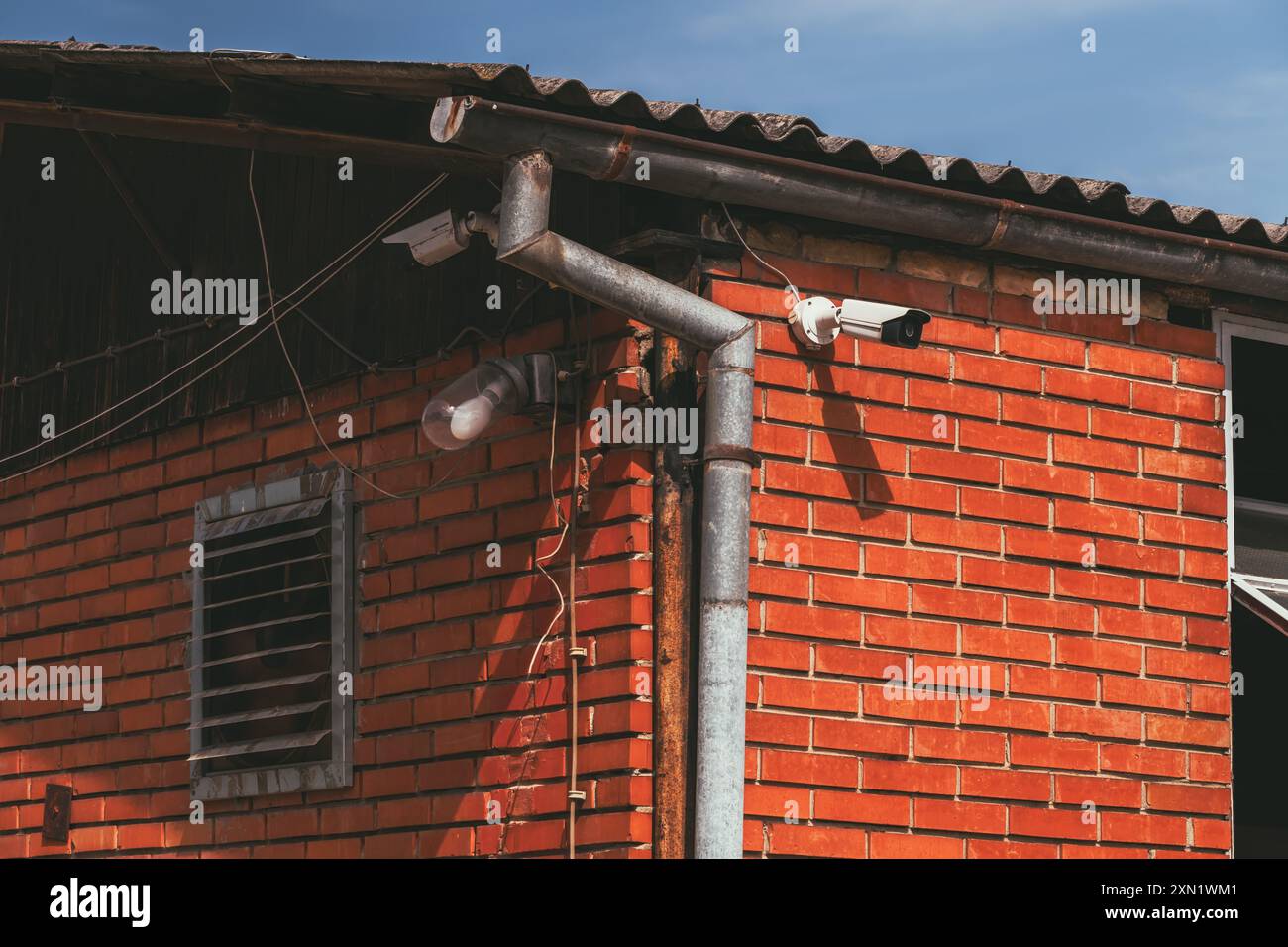 Vecchio edificio agricolo con ventilatore elettrico, lampadina esterna e telecamera di sicurezza, s elettiva Foto Stock