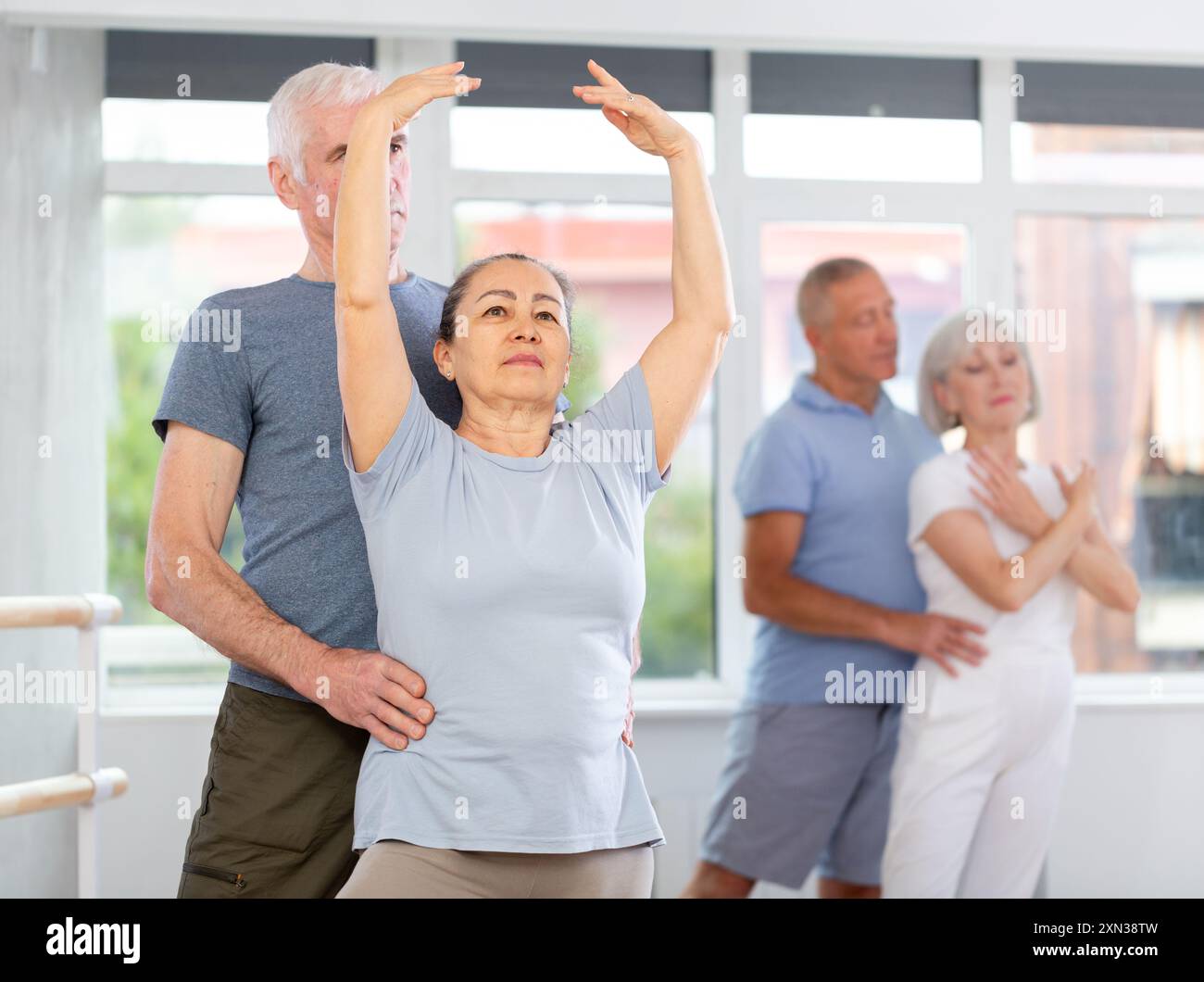 Coppia di ballerini maturi contemporanei che eseguono graziose coreografie, allenando il balletto entrechat in posa nella sala del balletto Foto Stock