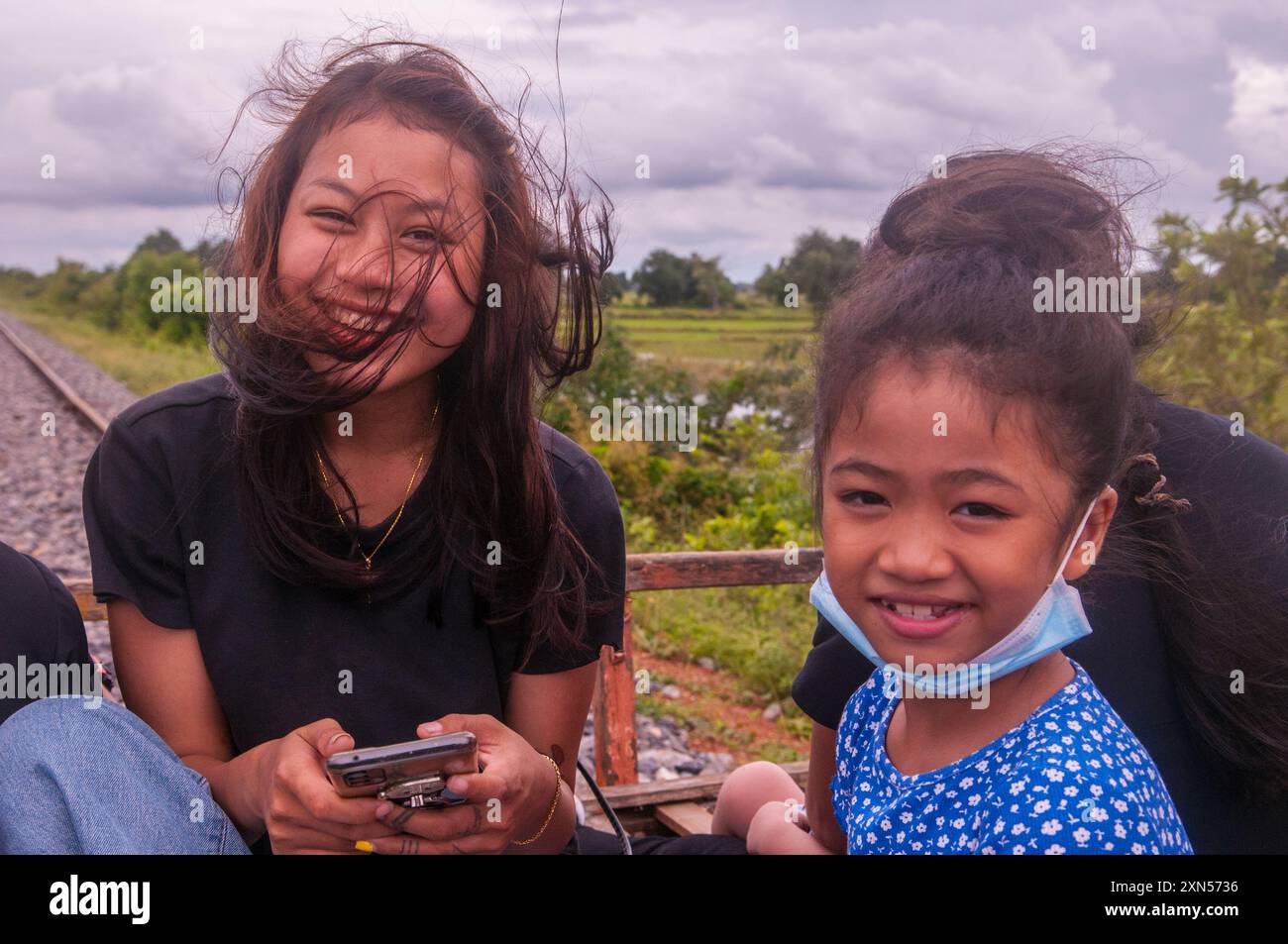 Una donna di corsa mista e una ragazza cambogiana di 9 anni viaggiano sul treno di bambù durante la pandemia di COVID-19. Provincia di Battambang, Cambogia. © Kraig Lieb Foto Stock