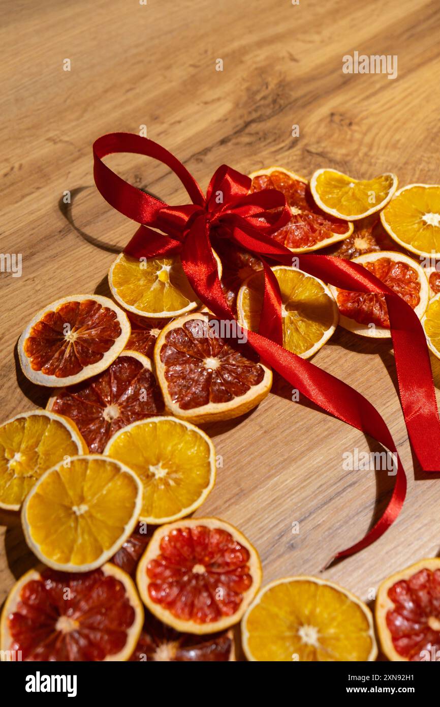 Istruzioni passo dopo passo sulla preparazione di una corona di Natale fatta a mano con frutta secca arance e pompelmo. Mani femminili che creano decorazioni artigianali fatte in casa. Festa di Capodanno. Vacanze invernali Foto Stock