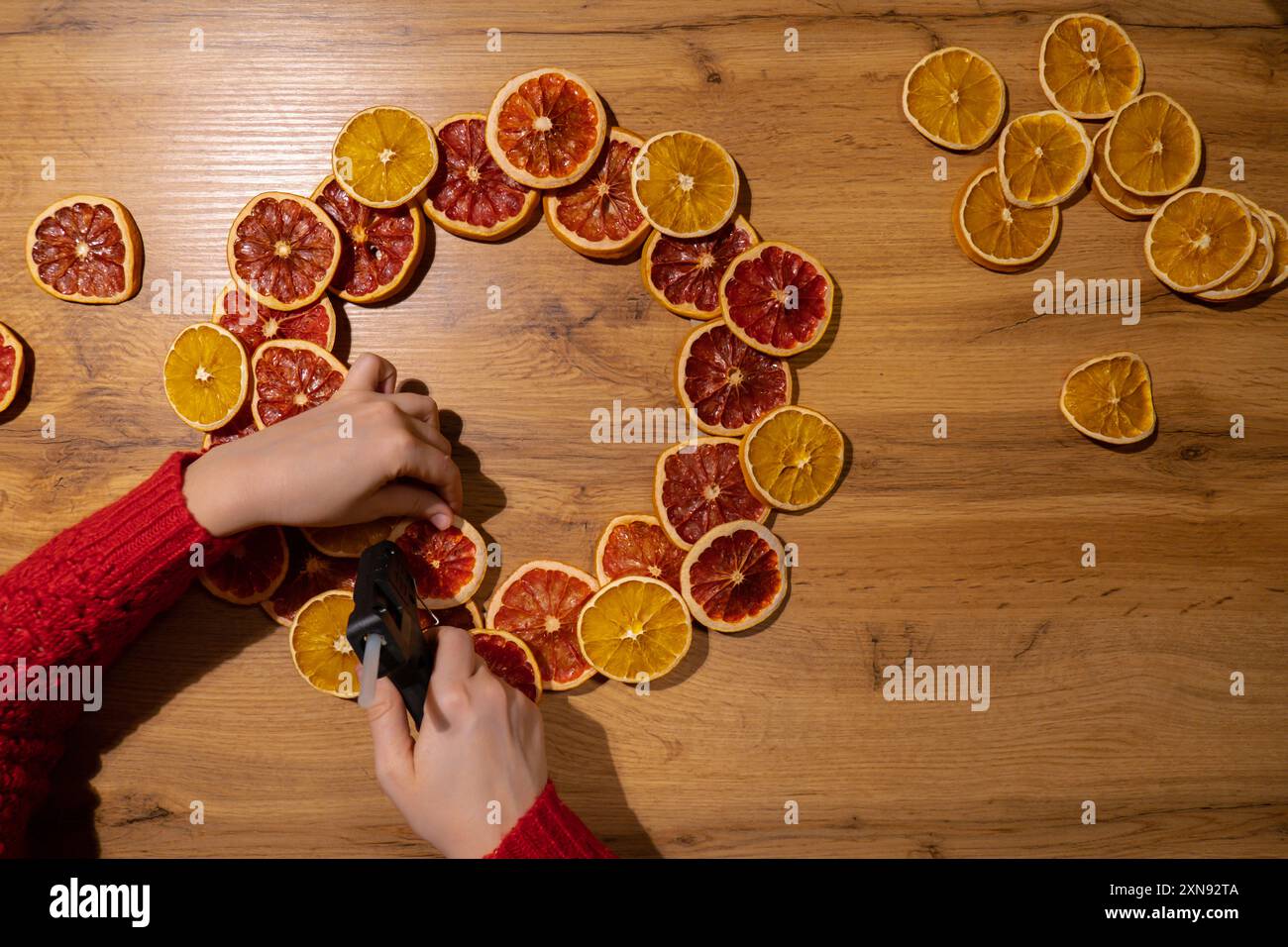 Processo fai-da-te di una donna che fa accordi natalizi con arance secche e pompelmo. Serie di istruzioni artigianali. Decorazioni ecologiche per le vacanze invernali a zero sprechi. Anno nuovo Foto Stock