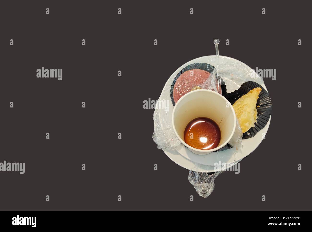 Tazza di caffè bianca vuota e spuntino residuo su un piatto bianco su sfondo nero. Scena dopo pranzo. Foto Stock