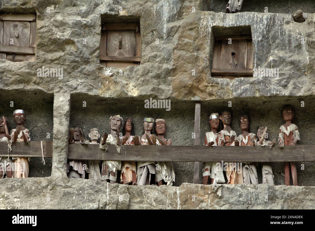 Aperture di tombe in pietra e effigi in legno su una scogliera in un tradizionale luogo di sepoltura a Lemo, Nord Toraja, Sud Sulawesi, Indonesia. Foto Stock