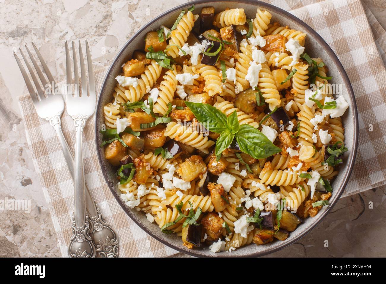 Piatto di pasta tradizionale con aglio saltato di melanzane e condito con primo piano di feta sulla ciotola sul tavolo. Vista dall'alto orizzontale Foto Stock