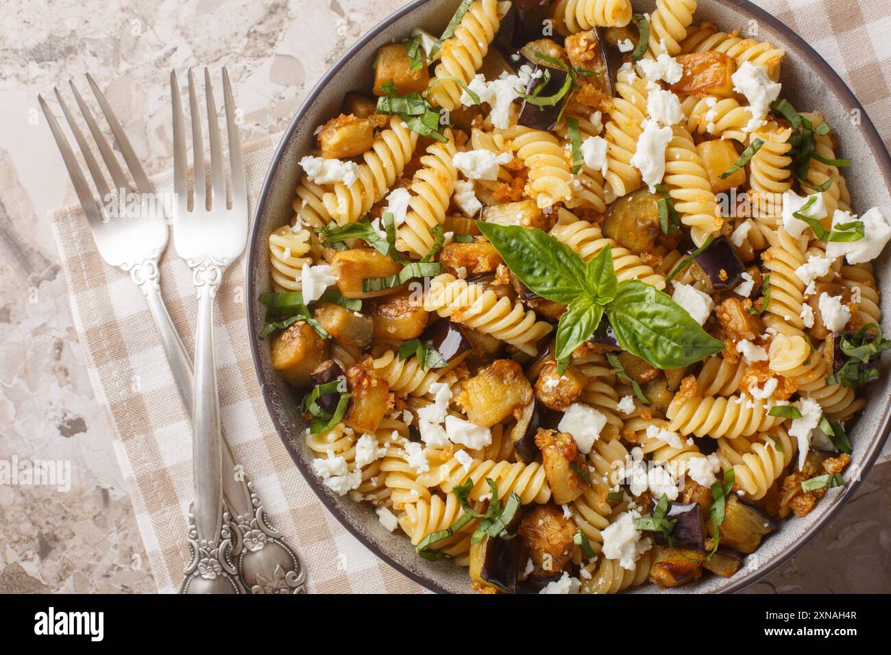 Cibo estivo pasta Fusilli con melanzane fritte, aglio e formaggio feta da vicino nel recipiente sul tavolo. Vista dall'alto orizzontale Foto Stock