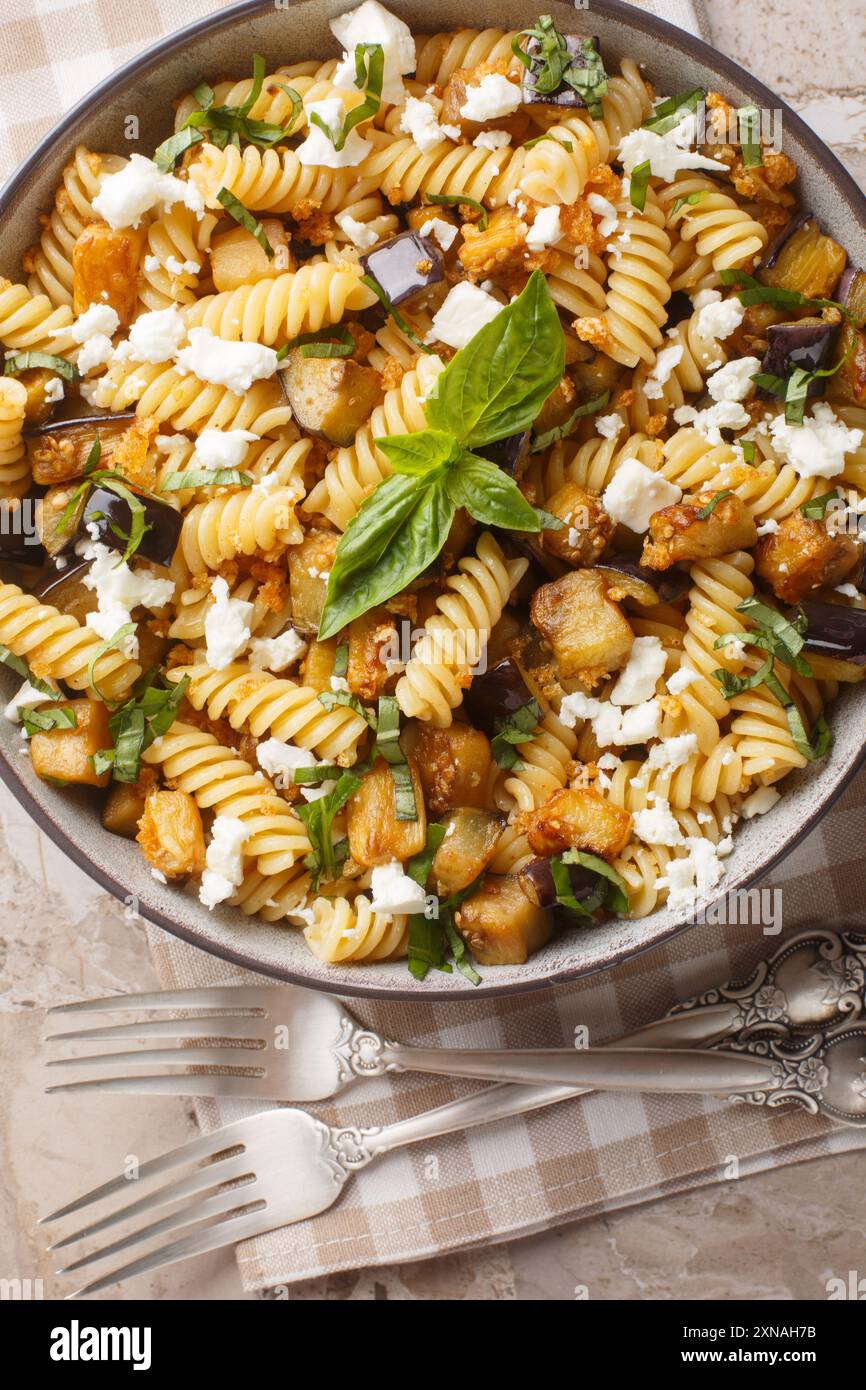 Pasta di melanzane Feta Garlicky con basilico e briciole di pane in primo piano sulla ciotola sul tavolo. Vista dall'alto verticale Foto Stock