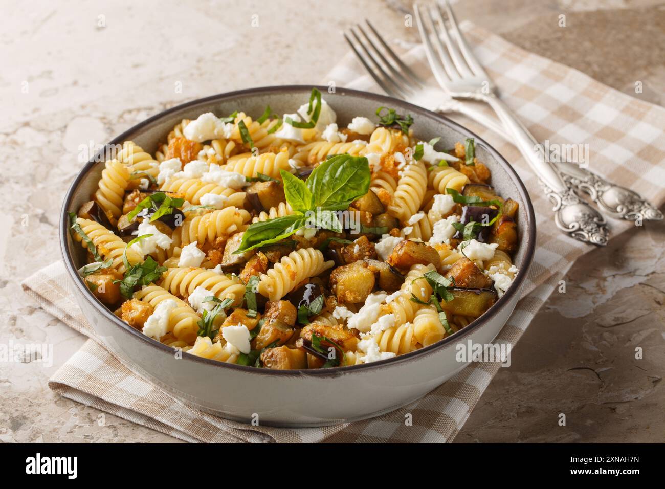 Pasta fusilli piccante con melanzane fritte, aglio, feta e pangrattato da vicino nel recipiente sul tavolo. Orizzontale Foto Stock