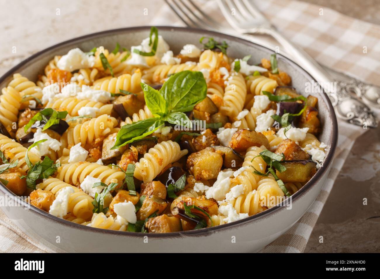 Cibo estivo pasta Fusilli con melanzane fritte, aglio e formaggio feta da vicino nel recipiente sul tavolo. Orizzontale Foto Stock