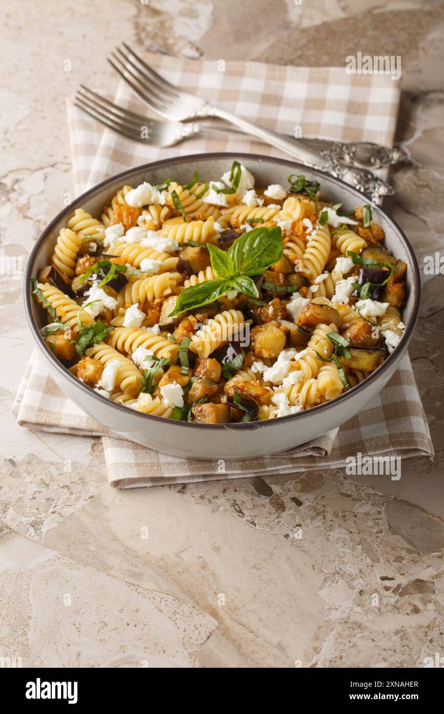 Fusilli con melanzane fritte, aglio e formaggio feta da vicino in una ciotola sul tavolo. Verticale Foto Stock