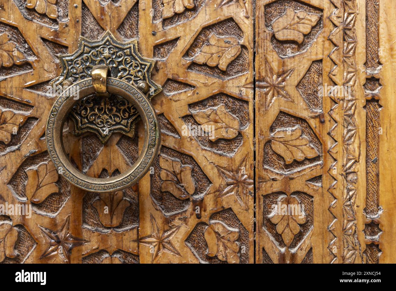 Antica maniglia rotonda in rame di una vecchia porta in legno decorata con ornamenti arabi scolpiti Foto Stock