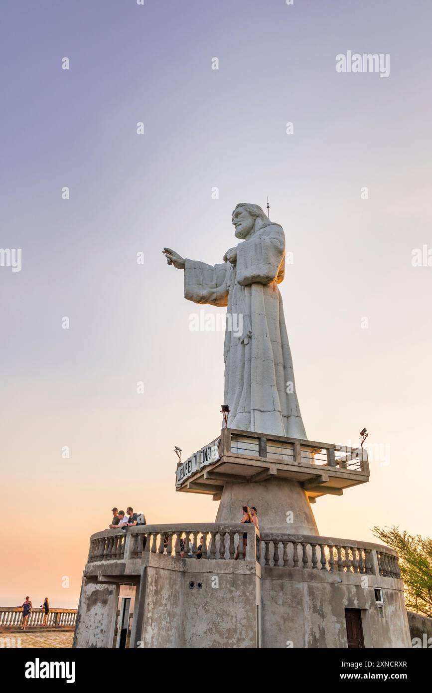 San Juan del Sur, Nicaragua - 23 marzo 2024: Imponente statua contemporanea del Cristo della Misericordia in piedi su una scogliera sopra la baia di San Juan del Sur. Foto Stock