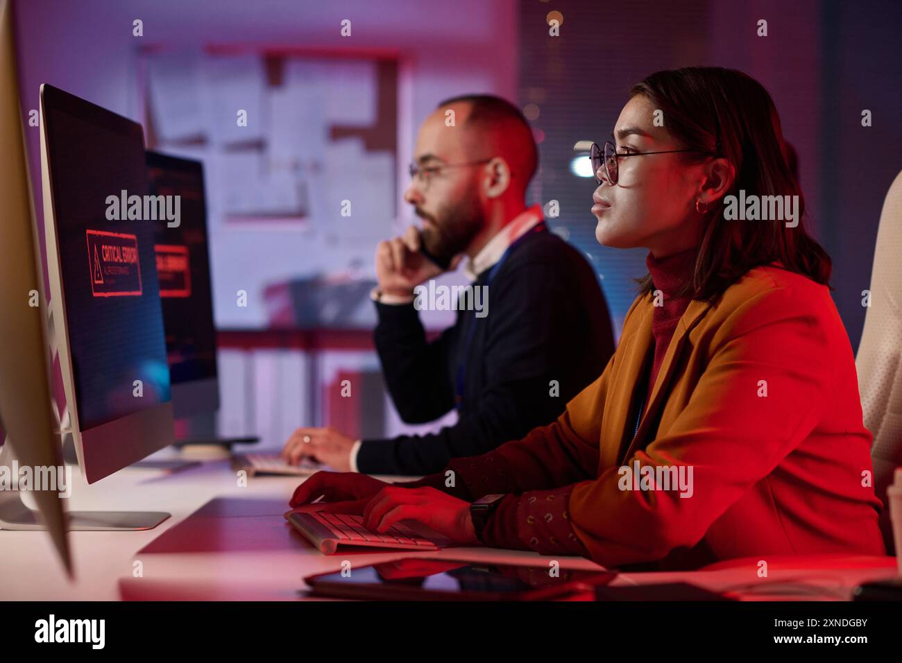 Immagine laterale di programmatori informatici che lavorano nel dipartimento di sicurezza informatica con luci di emergenza rosse spazio di copia Foto Stock