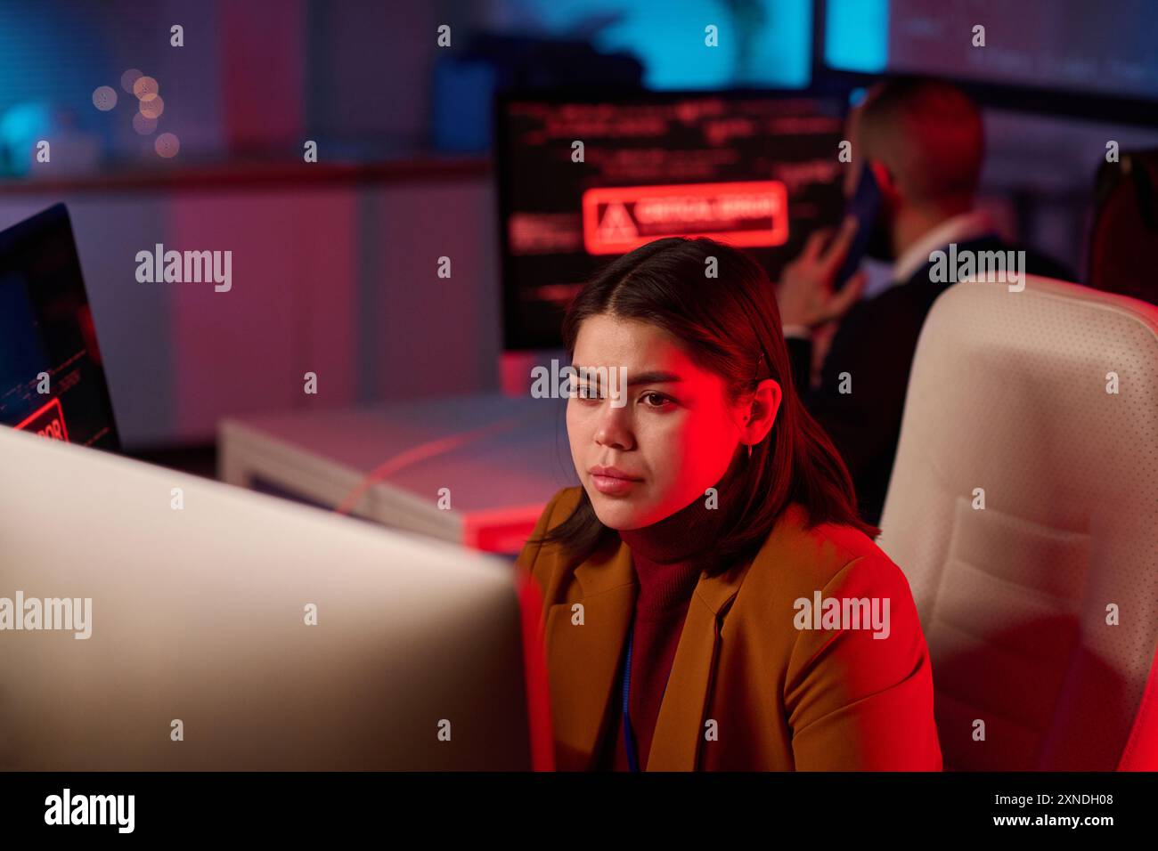 Ritratto di una giovane donna che usa un computer nel dipartimento di sicurezza informatica illuminato da uno spazio di copia rosso al neon Foto Stock