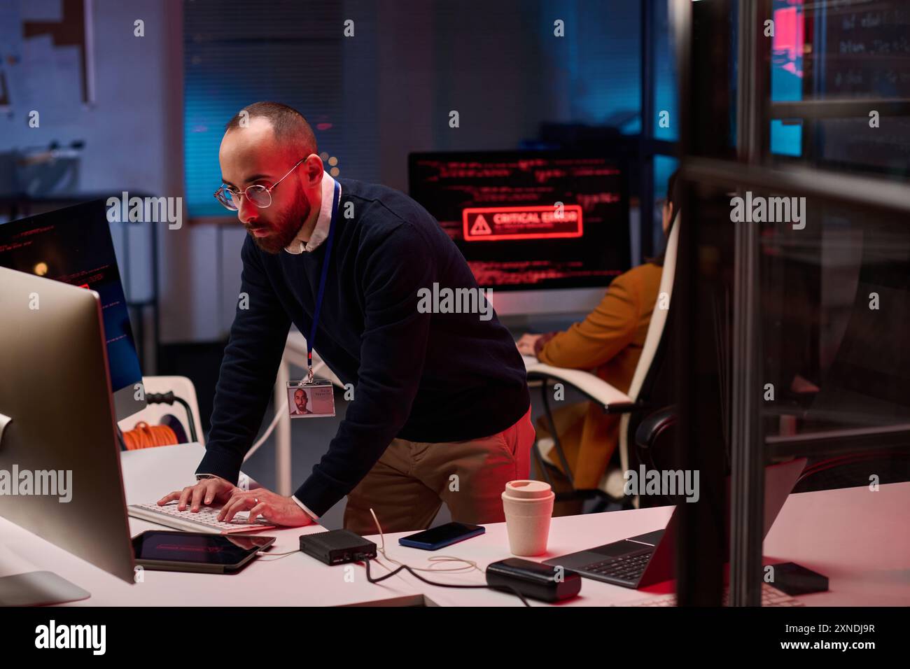 Dipartimento di sicurezza informatica in emergenza con uomo adulto che utilizza computer in rosso luci al neon spazio copia Foto Stock