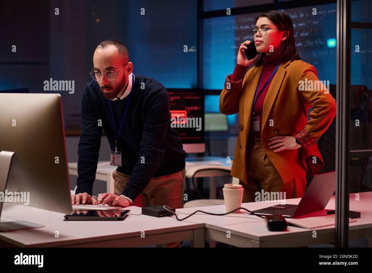 Dipartimento di sicurezza informatica in emergenza con due persone che usano computer e parlano al telefono hacking nel sistema Foto Stock