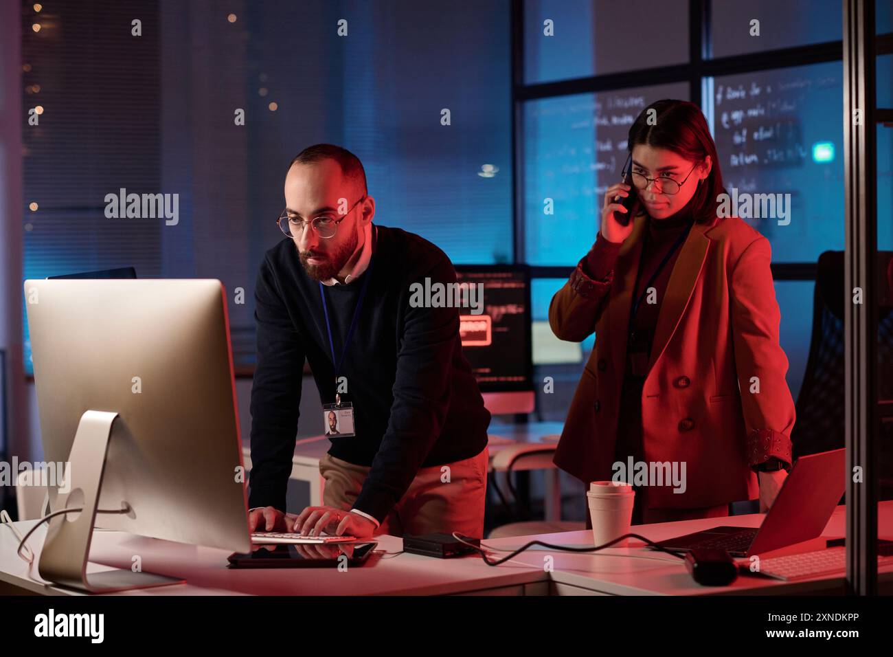 Ritratto di due persone che lavorano nel dipartimento di sicurezza informatica con luce al neon rossa situazione di emergenza critica Foto Stock