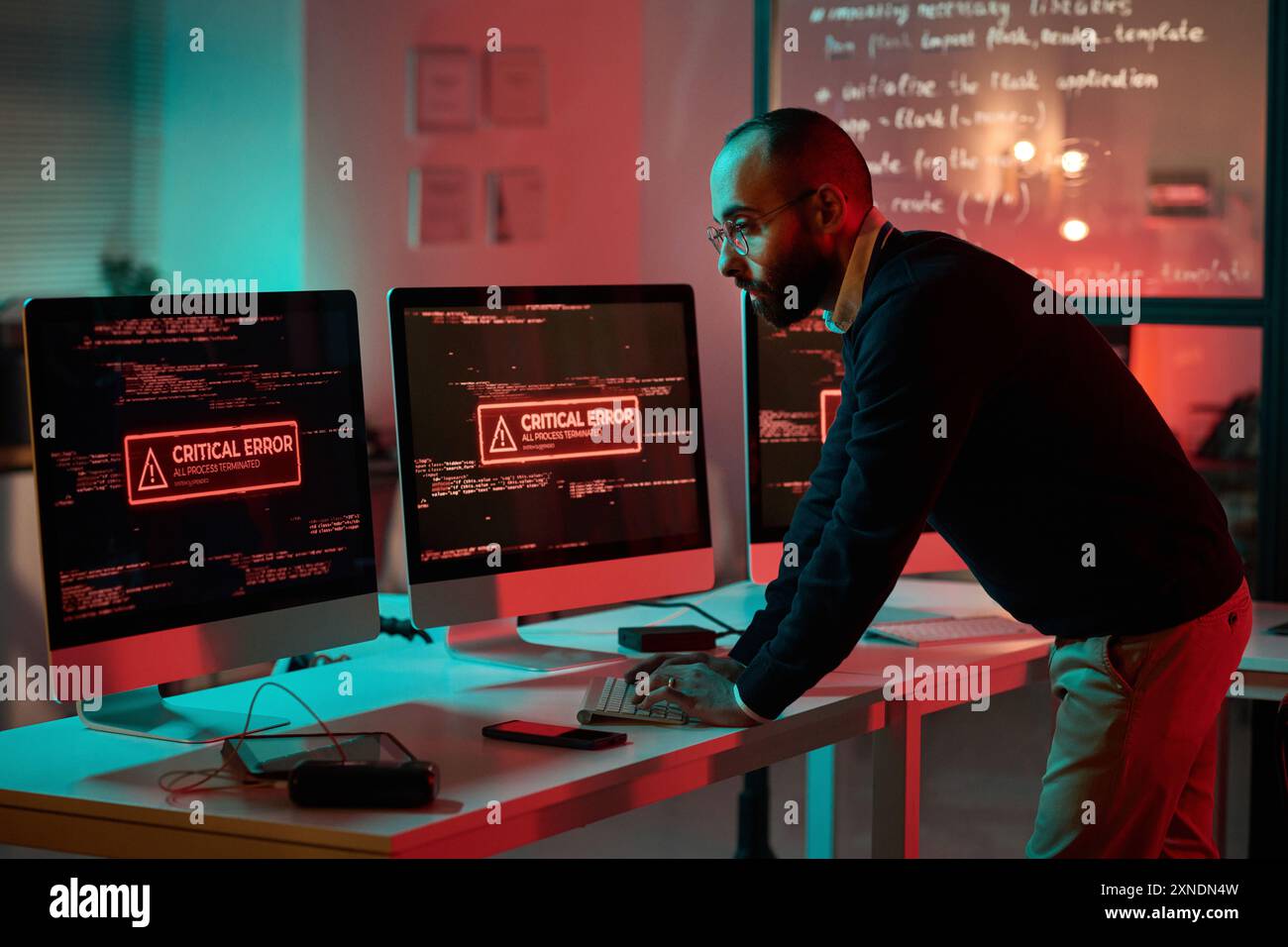 Immagine laterale di un esperto di cybersecurity adulto che lavora in caso di emergenza e utilizza un computer con messaggio di errore critico sullo schermo Foto Stock