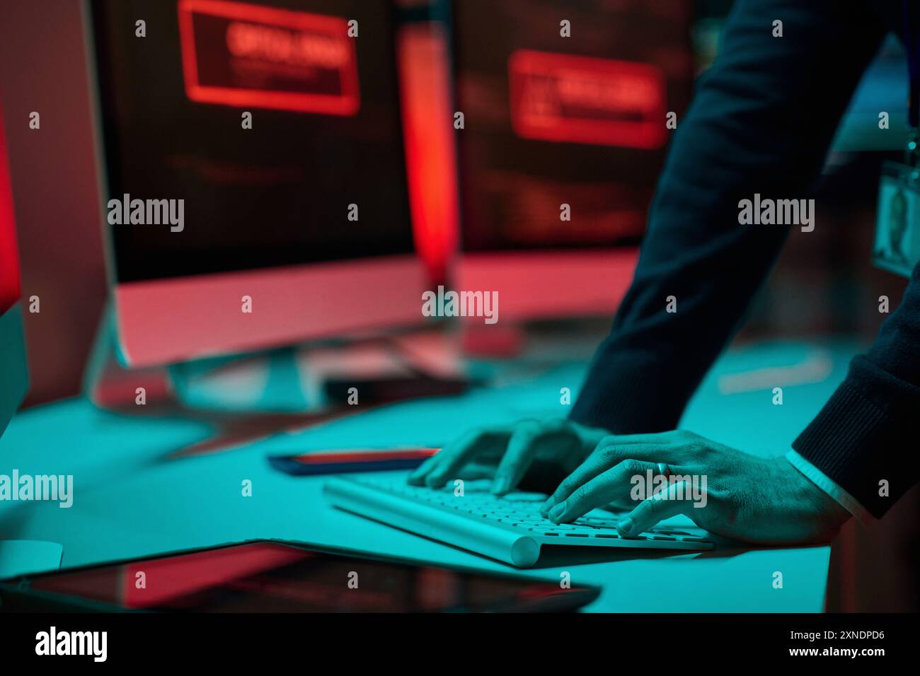 Primo piano di un uomo irriconoscibile che digita sulla tastiera del computer con luce blu e rossa nello spazio di copia del dipartimento di sicurezza informatica Foto Stock