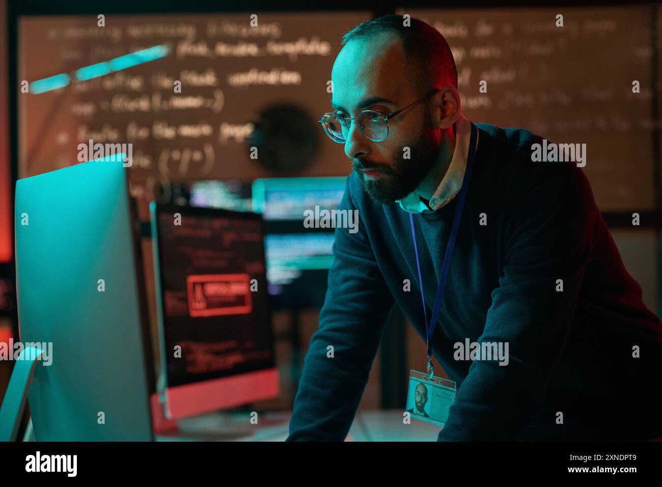 Ritratto di uomo adulto barbuto che indossa occhiali e che utilizza il computer che impedisce l'emergenza nello spazio di copia del dipartimento di sicurezza informatica Foto Stock