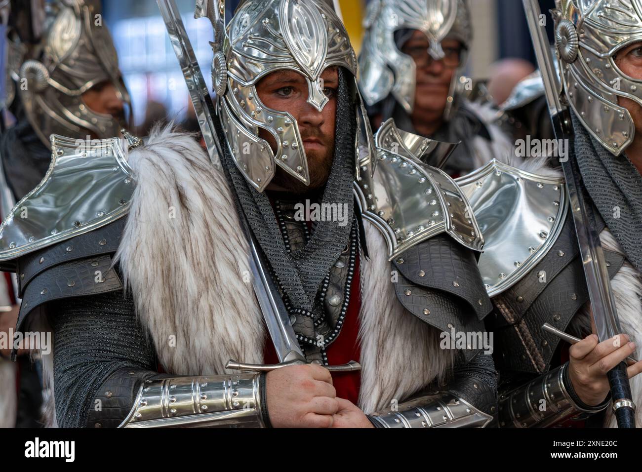 Questa immagine cattura un gruppo di individui vestiti da cavalieri, adornati da luccicanti armature e caschi, con sciabole che poggiano sulle spalle. Foto Stock