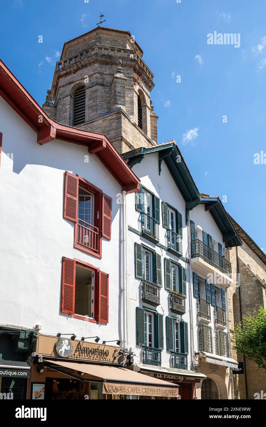 Francia, regione Nouvelle-Aquitania, Saint-Jean-de-Luz, negozi tradizionali e gelato in Rue Léon Gambetta con la Chiesa di San Giovanni Battista oltre Foto Stock