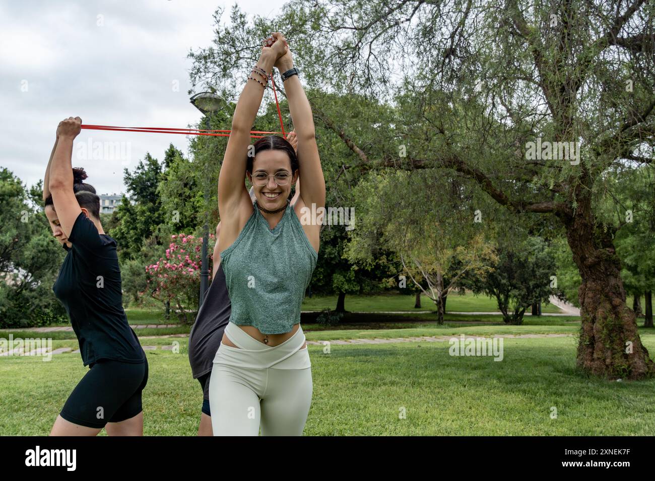 Un gruppo diversificato di persone si sta allenando con bande di resistenza in un parco, concentrandosi sul fitness e il benessere Foto Stock