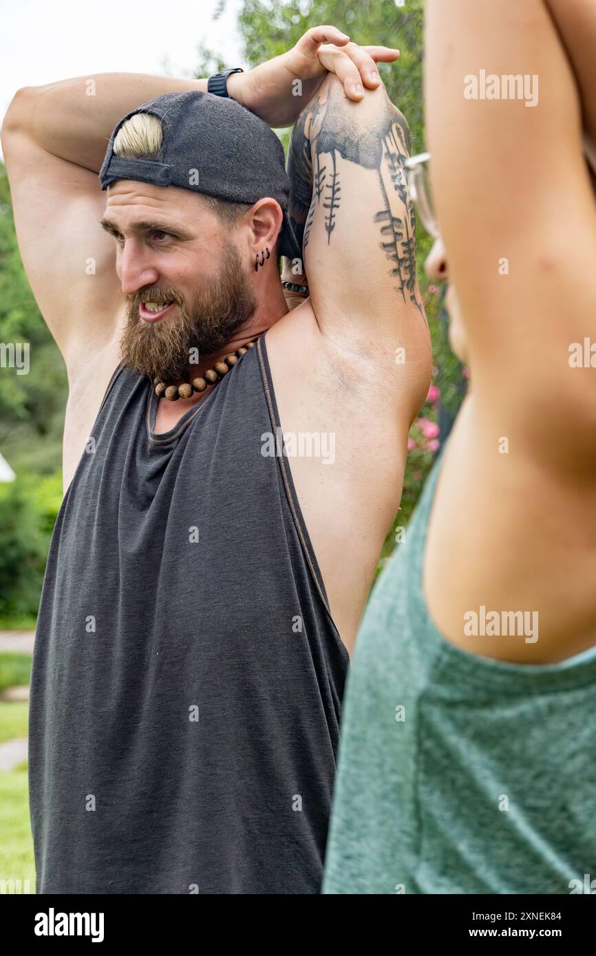 Gli atleti allungano le braccia all'aperto prima di iniziare la lezione. Questa routine riflette la loro attenzione al benessere e all'impegno per una vita sana, en Foto Stock