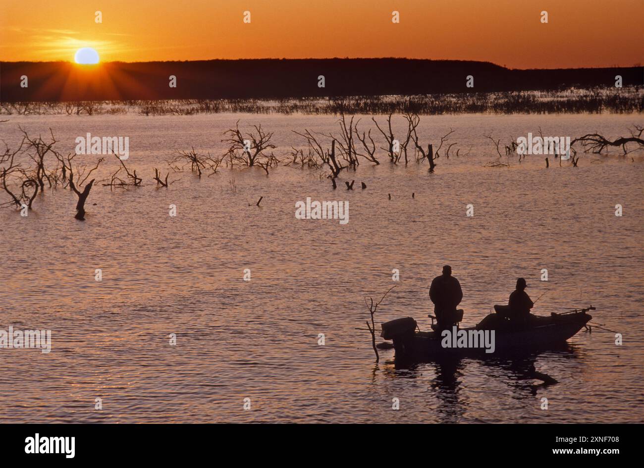 Pescatori in barca vicino alla rampa di Frio Bend, al lago artificiale Choke Canyon, al parco statale Choke Canyon, al tramonto, primavera, regione del Texas meridionale, Texas, STATI UNITI Foto Stock