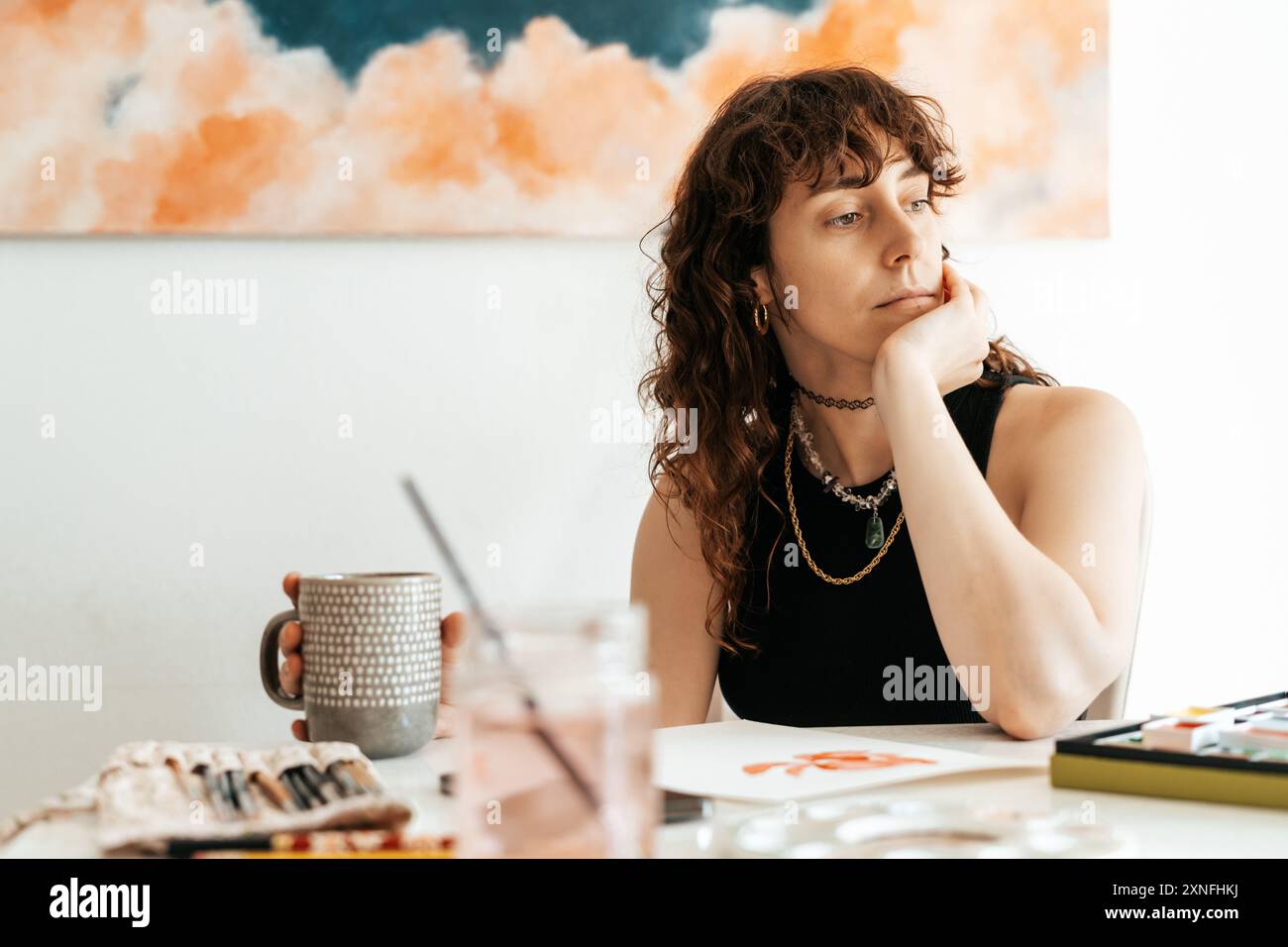 una donna artista si prende una pausa mentre tiene una tazza Foto Stock