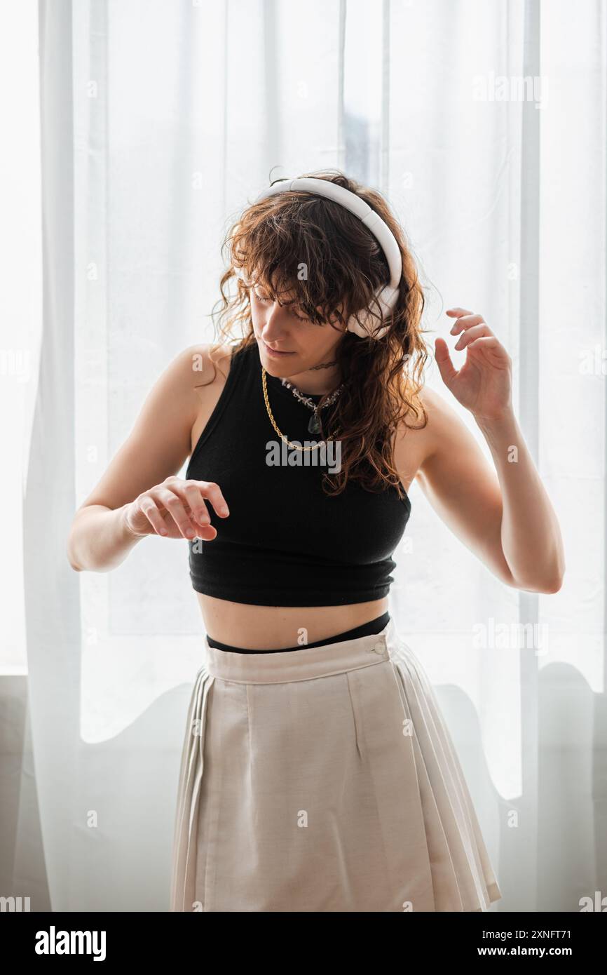 la donna balla davanti alla finestra mentre ascolta la musica con le cuffie Foto Stock