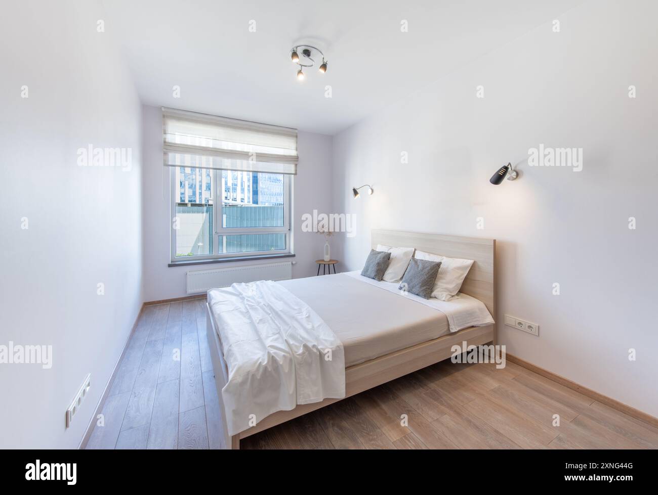 Camera da letto con letto matrimoniale king size, pavimento in legno e finestra sullo sfondo. Casa. Di giorno Foto Stock