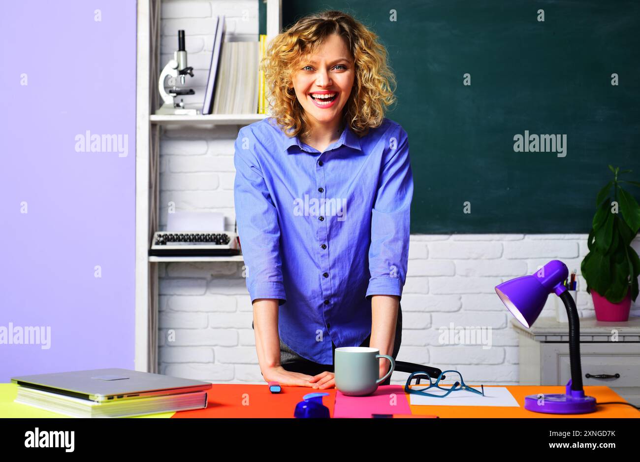 Insegnante di scuola sorridente, tutor universitario in piedi alla scrivania in classe. La giovane studentessa risponde all'esame davanti alla lavagna. Apprendimento, istruzione e k Foto Stock