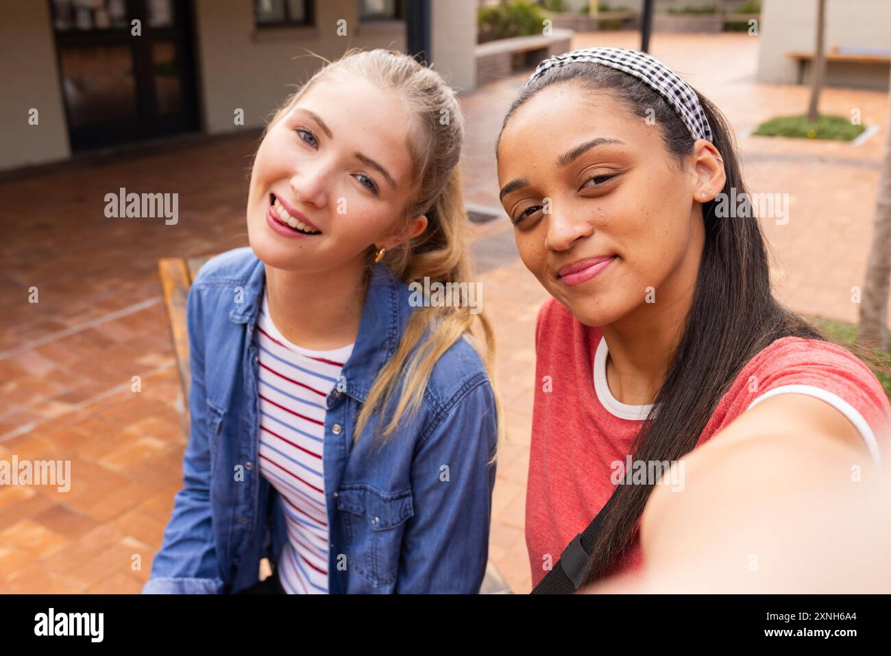 Le adolescenti sorridono e si fanno selfie insieme nel cortile delle superiori Foto Stock