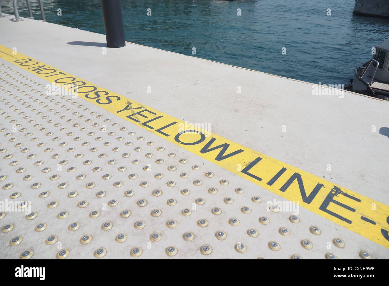 Cartello di avvertenza situato sulla banchina è vietato attraversare la linea gialla distinta Foto Stock