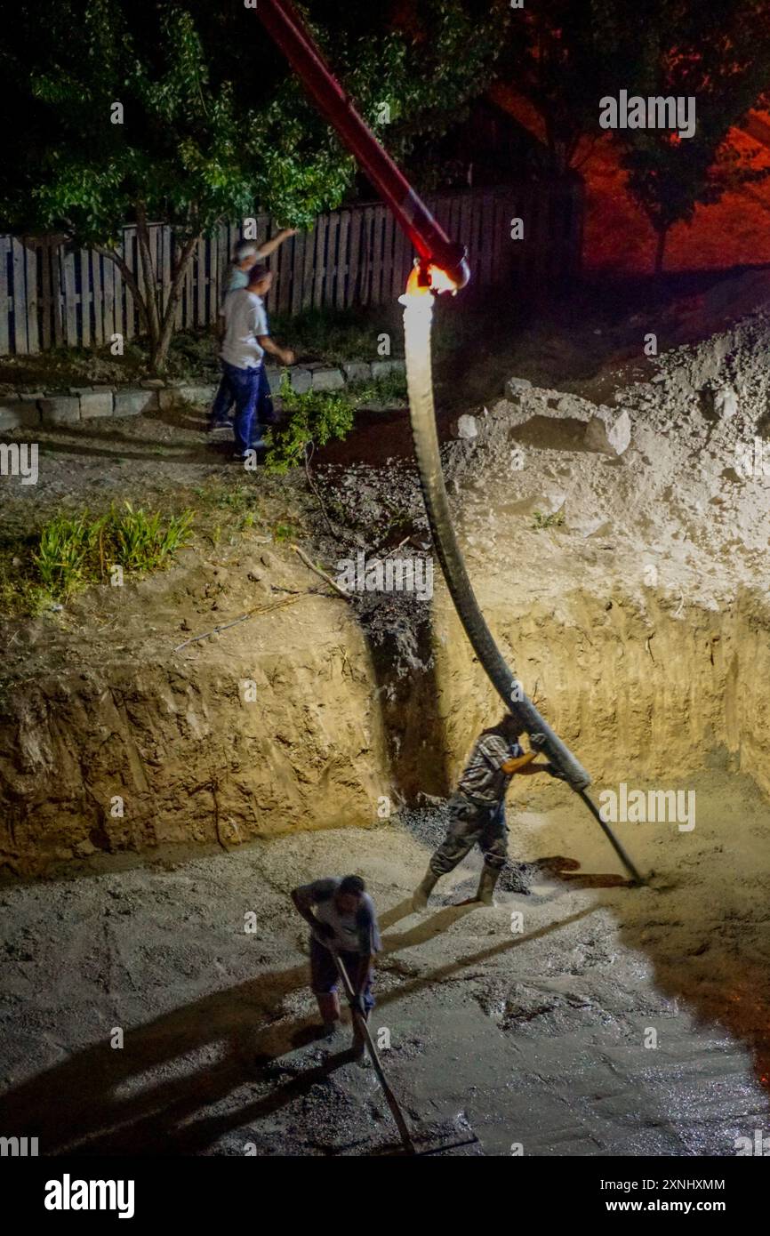 17 agosto 2023 Eskisehir Turchia. Uomini di costruzione che versano cemento sulle fondamenta della costruzione di notte Foto Stock