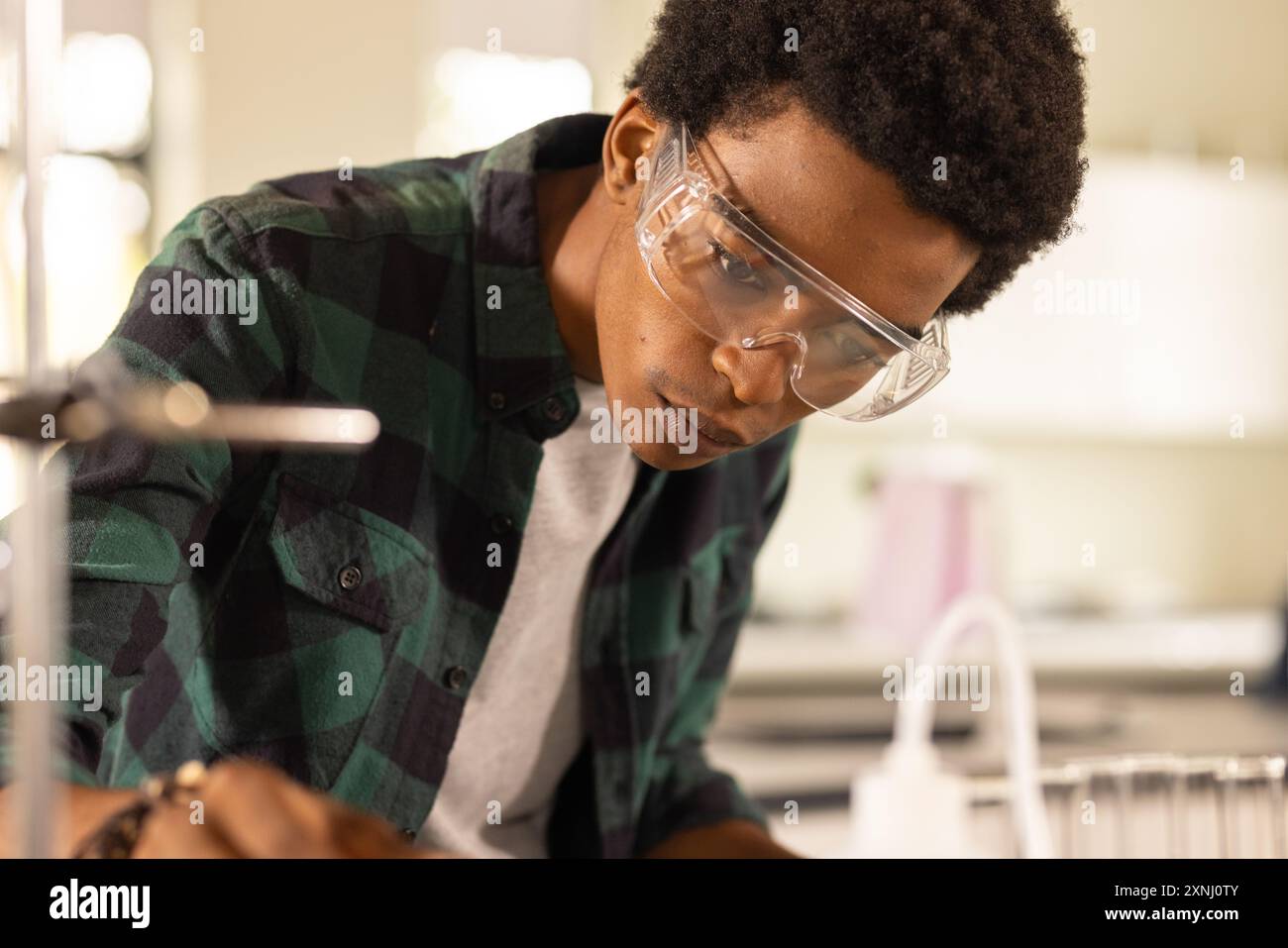 Indossando occhiali di sicurezza, adolescente che conduce esperimenti scientifici in classe liceale Foto Stock