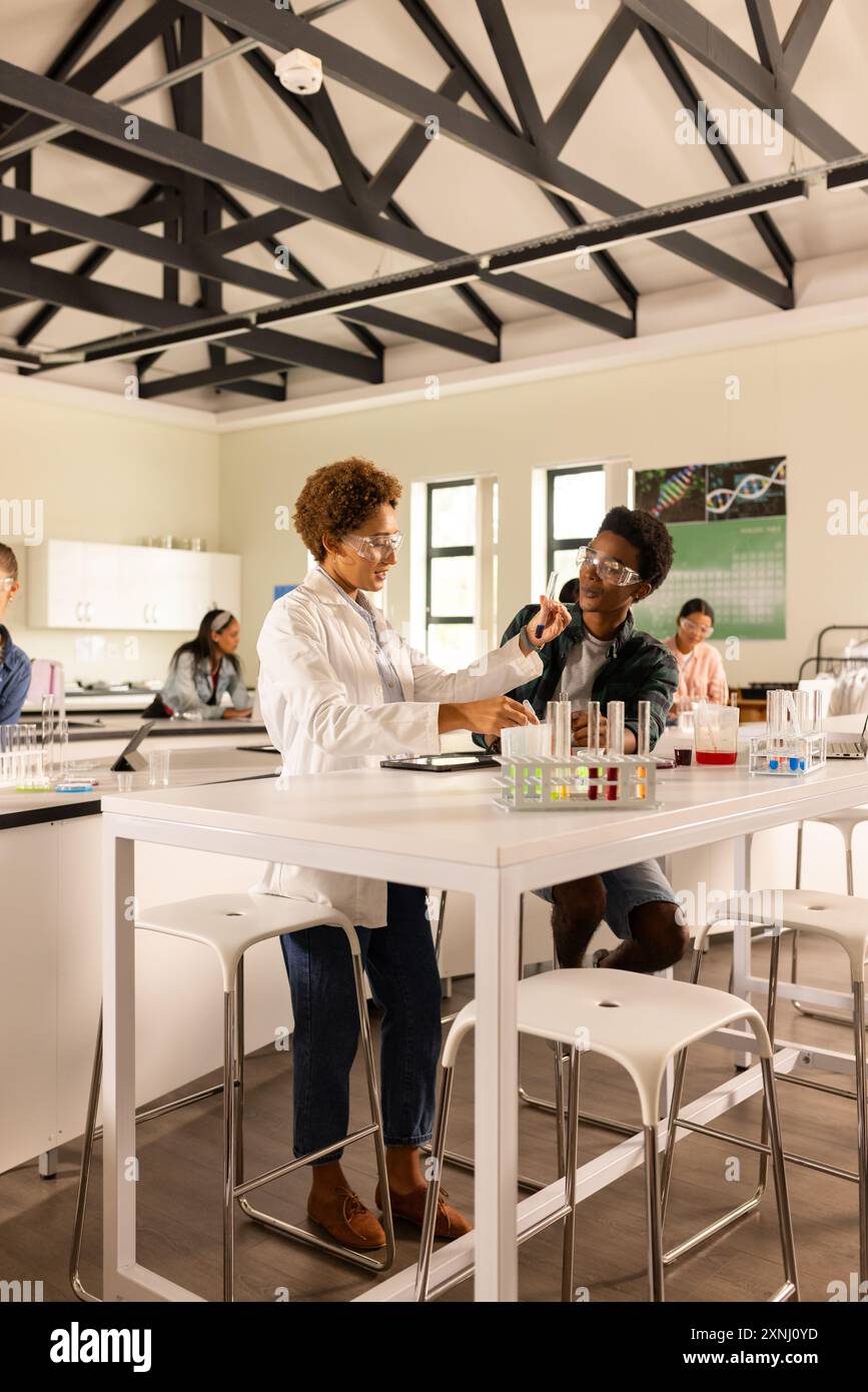 Nel laboratorio del liceo, insegnante e studente che conducono esperimenti con provette Foto Stock