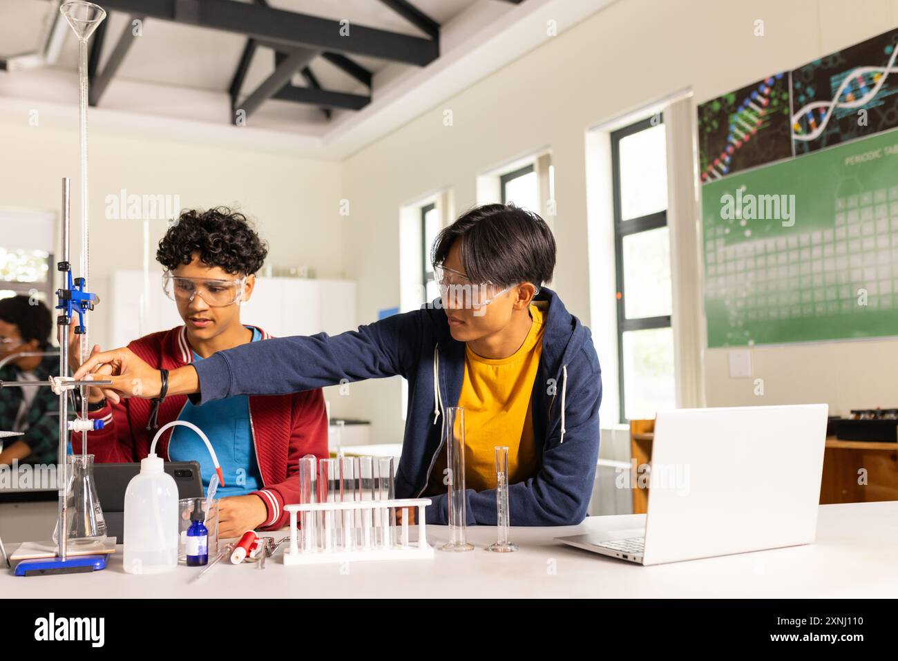 Al liceo, gli adolescenti conducono esperimenti scientifici con attrezzature da laboratorio e laptop Foto Stock