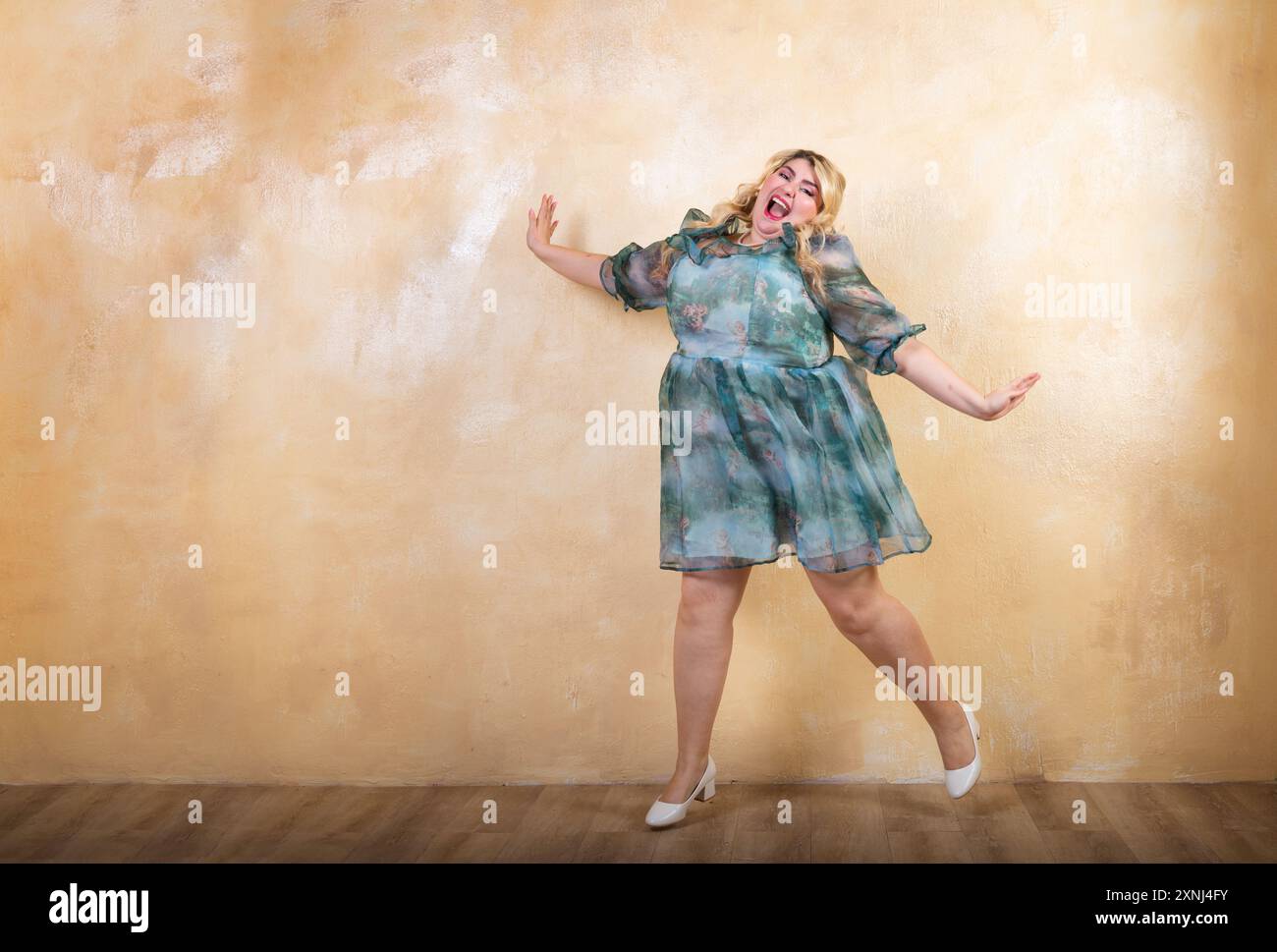 Il modello allegro e curvato sta saltando in uno studio, esprimendo gioia e fiducia in se stesso Foto Stock