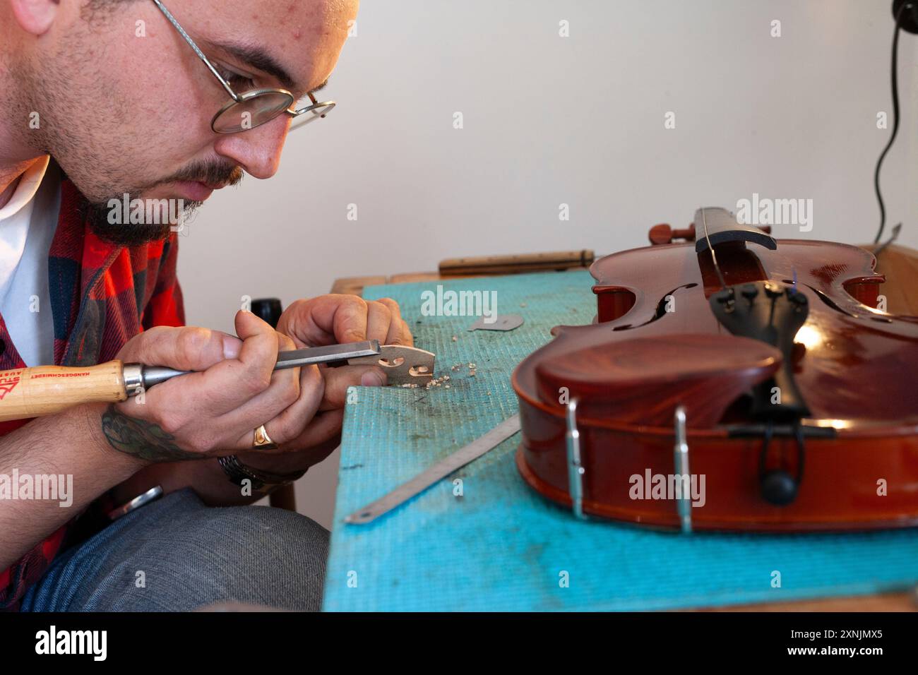 Liutaio che ripara e aggiorna violino a buon mercato Foto Stock