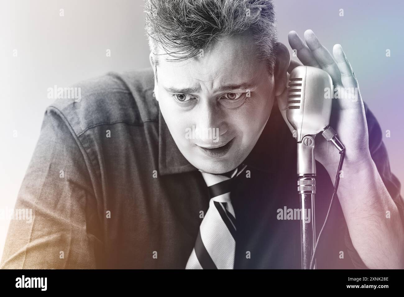 l'uomo con una camicia scura e una cravatta a righe regge un microfono stravagante, simboleggiando la metafora dell'uso inappropriato e incompetente degli strumenti. Il suo "expressi" Foto Stock