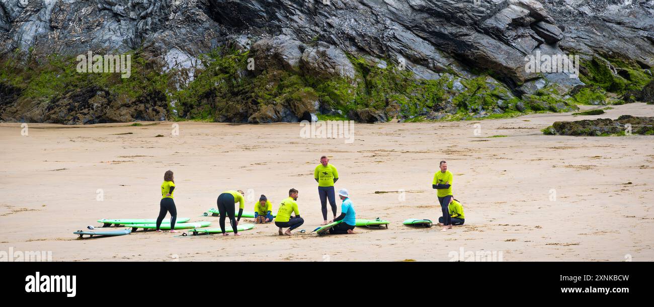 Un'immagine panoramica di un istruttore di surf della Escape Surf School con i suoi studenti principianti all'inizio di una lezione di surf a Towan Beac Foto Stock