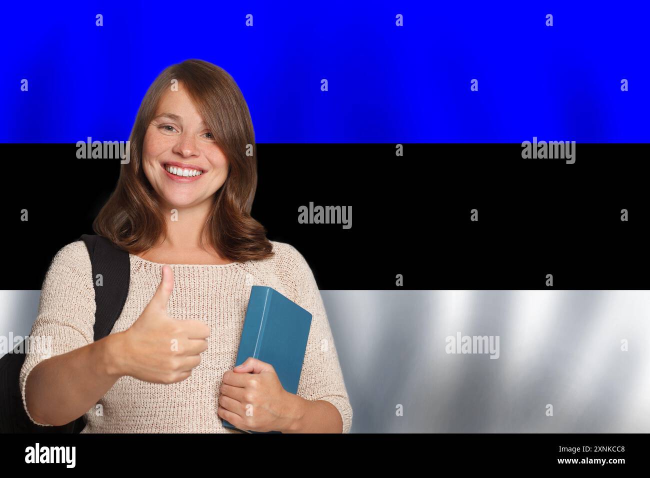 Una bella studentessa amichevole sullo sfondo della bandiera estone. Concetto di viaggio, istruzione e apprendimento della lingua in Estonia Foto Stock