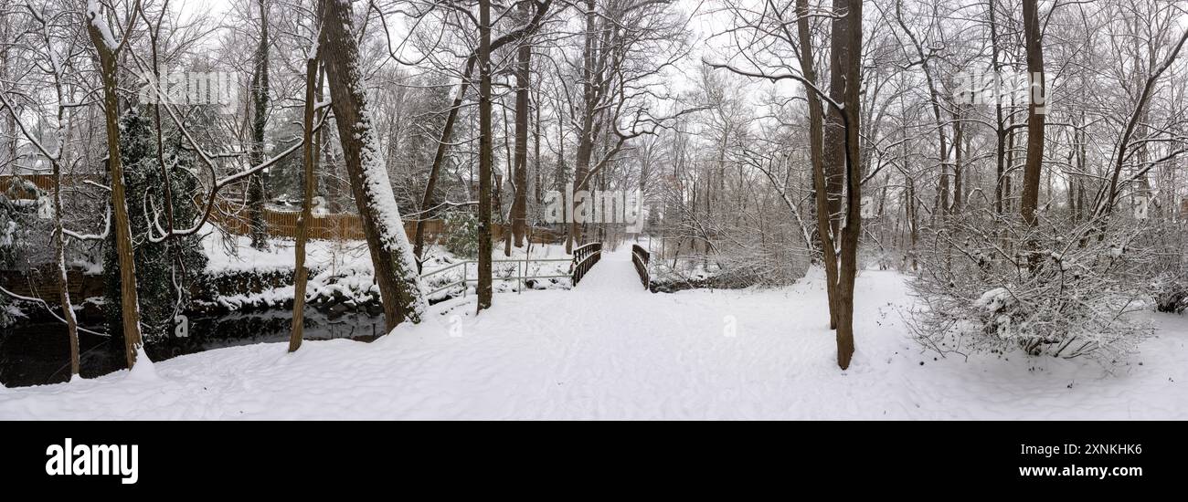 Vista panoramica invernale ad alta risoluzione del Snow-covered Rock Spring Park ad Arlington, Virginia // ARLINGTON, Virginia - Una vista panoramica ad alta risoluzione cattura il paesaggio invernale innevato del Rock Spring Park, un santuario boscoso di due ettari che conserva un corridoio storicamente significativo dove i sentieri di pesca dei nativi americani un tempo collegavano i villaggi dell'entroterra alla pesca sul fiume Potomac. Situato al 5012 di Little Falls Road, il parco prende il nome dalle sorgenti naturali che storicamente emersero dal terreno roccioso della zona. Il parco si trova alle sorgenti di Four Mile Run, mentre Little Pimm Foto Stock