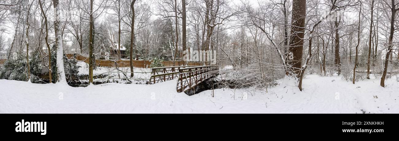 Vista panoramica invernale ad alta risoluzione del Snow-covered Rock Spring Park ad Arlington, Virginia // ARLINGTON, Virginia - Una vista panoramica ad alta risoluzione cattura il paesaggio invernale innevato del Rock Spring Park, un santuario boscoso di due ettari che conserva un corridoio storicamente significativo dove i sentieri di pesca dei nativi americani un tempo collegavano i villaggi dell'entroterra alla pesca sul fiume Potomac. Situato al 5012 di Little Falls Road, il parco prende il nome dalle sorgenti naturali che storicamente emersero dal terreno roccioso della zona. Il parco si trova alle sorgenti di Four Mile Run, mentre Little Pimm Foto Stock