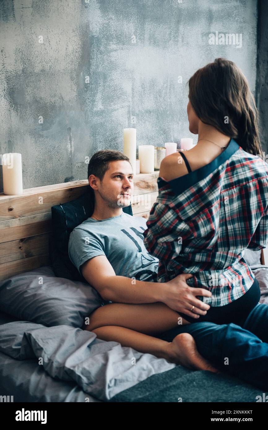 un ragazzo e una ragazza si siedono sul letto della camera e si guardano l'un l'altro Foto Stock