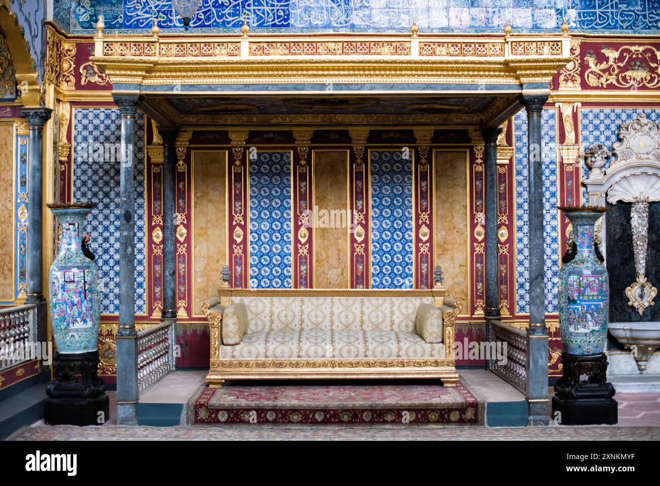 Palazzo Topkapi Harem Trono Imperiale Istanbul Turchia // ISTANBUL, Turchia — il trono imperiale ornato nella Hünkar Sofası (sala del Trono Imperiale) dell'Harem del Palazzo Topkapi, Istanbul. Questa sede riccamente decorata, adornata con metalli preziosi, pietre preziose e intricata artigianato, servì come fulcro per il pubblico privato del Sultano ottomano all'interno degli isolati confini dell'harem imperiale. Il trono simboleggia l'opulenza e l'autorità dell'Impero Ottomano, riflettendo la maestria artistica e il patrimonio culturale del periodo. Foto Stock