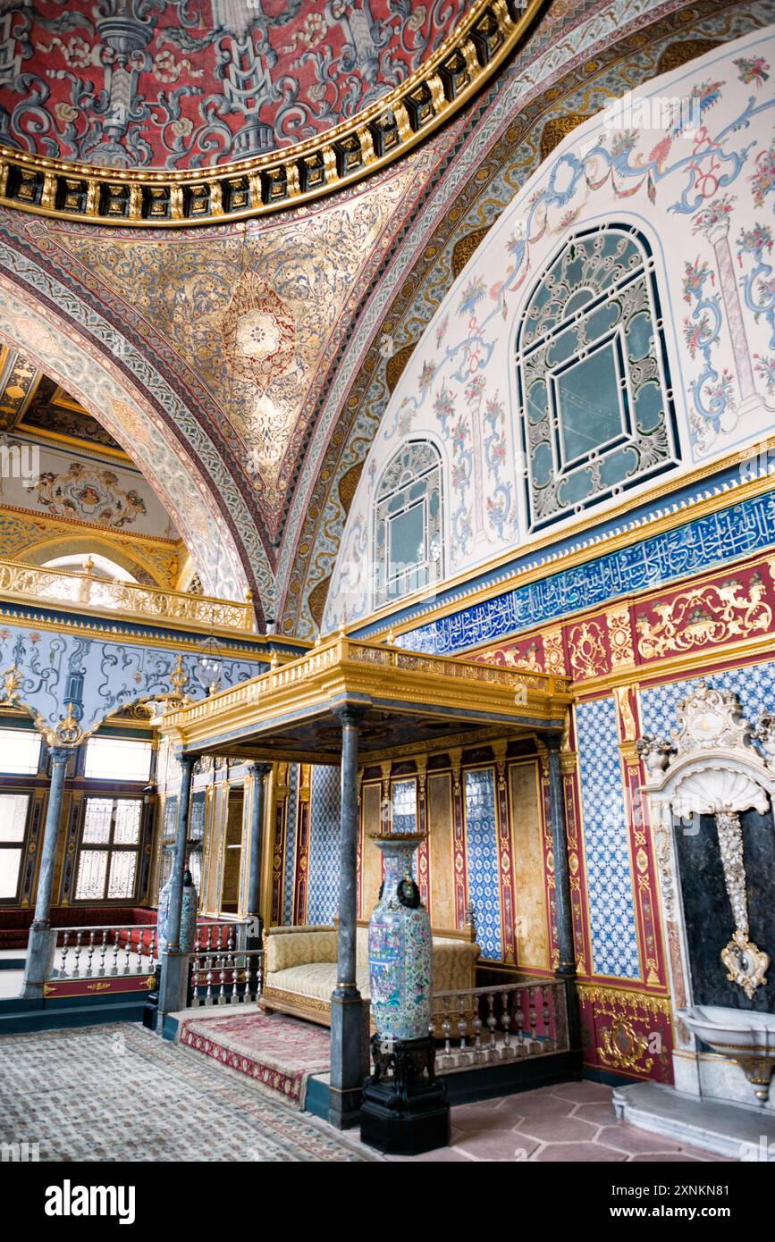 Palazzo Topkapi Harem sala del Trono Imperiale Istanbul Turchia // ISTANBUL, Turchia — il trono imperiale ornato nella Hünkar Sofası (sala del Trono Imperiale) dell'Harem del Palazzo Topkapi, Istanbul. Questa sede riccamente decorata, adornata con metalli preziosi, pietre preziose e intricata artigianato, servì come fulcro per il pubblico privato del Sultano ottomano all'interno degli isolati confini dell'harem imperiale. Il trono simboleggia l'opulenza e l'autorità dell'Impero Ottomano, riflettendo la maestria artistica e il patrimonio culturale del periodo. Foto Stock