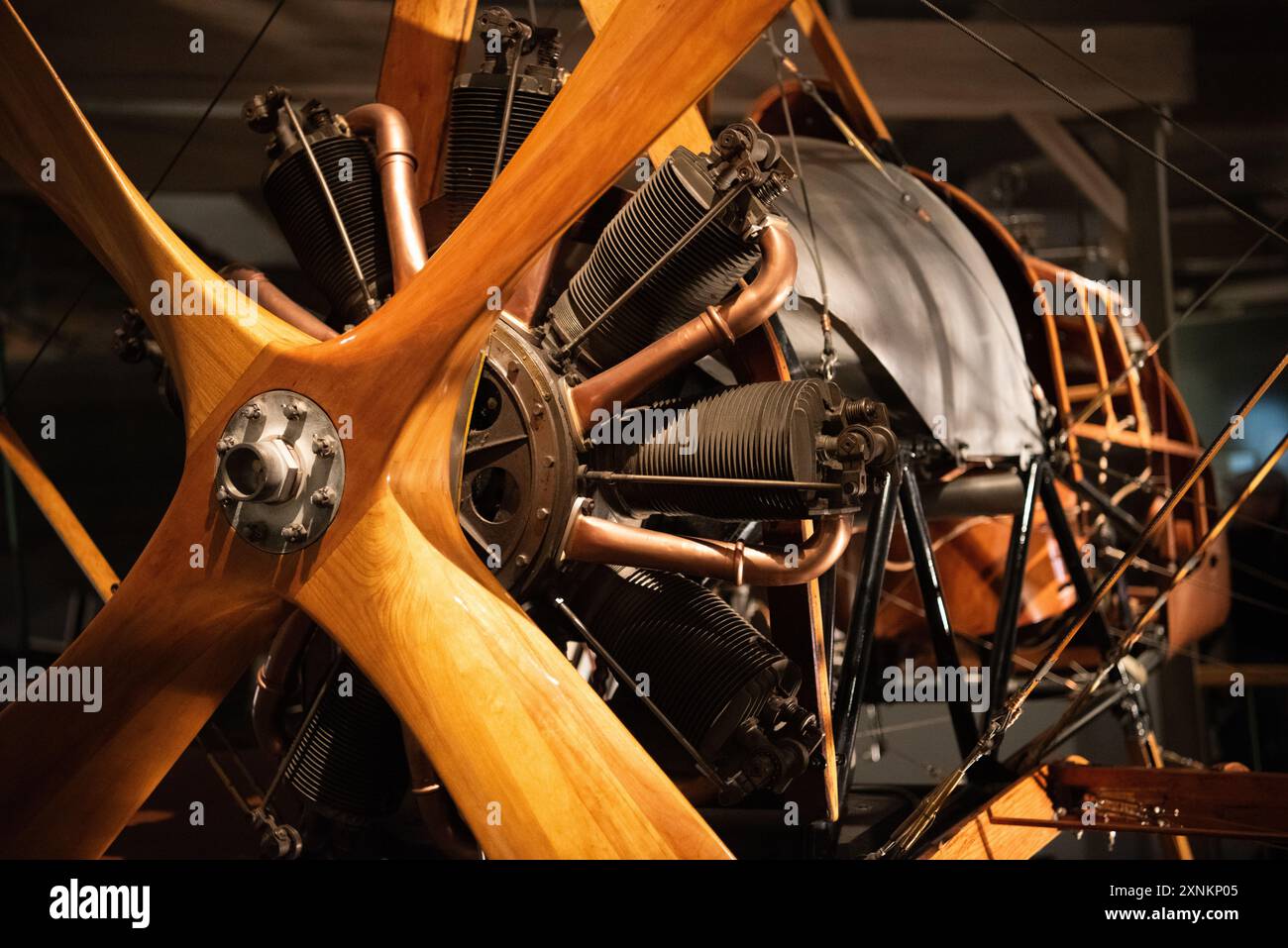 WWI Biplane Wooden Propeller Rotary Engine Close Up Air and Space Museum | WASHINGTON D.C., Stati Uniti - Un'elica in legno scolpito a quattro pale incornicia i cilindri esposti e le tubazioni in rame di un primo motore rotativo o radiale per aerei presso lo Smithsonian National Air and Space Museum. I motori rotativi dell'era della prima guerra mondiale ruotavano l'intero monoblocco con l'elica, generando una coppia giroscopica così forte che i piloti in genere preferivano le svolte in una direzione rispetto all'altra. Foto Stock