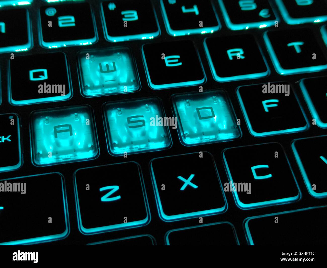 Primo piano di una tastiera RGB retroilluminata di colore blu su un computer portatile da gioco in ambienti bui. Immagine con messa a fuoco selettiva Foto Stock